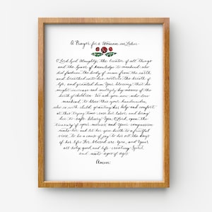 May include: A framed print with a black and white calligraphy prayer for a woman in labor. The prayer is written in a cursive script with a floral design at the top. The text reads: "A Prayer for a Woman in Labor O Lord God Almighty, the Creator of all things and the Giver of knowledge to mankind who did fashion the body of man from the earth and breathed into his nostrils the breath of life, and granted him Your blessing that he might increase and multiply by means of the birth of children. We ask You now who love mankind, to bless this Your handmaiden, who is with child, granting her help and comfort at this trying time, ease her labor, and bring her to safe delivery. Yea, Lord, open the treasury of Your mercies and Your compassion unto her, and let her give birth to a fruitful vine, to be a cause of joy to her all the days of her life. For blessed are You, and Your all-holy, good, and life-creating Spirit, and unto ages of ages. Amen."