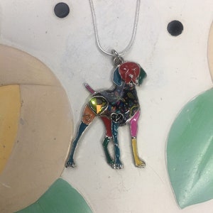 May include: A colorful, multi-colored enamel dog pendant necklace. The pendant is a silhouette of a dog with a silver chain.