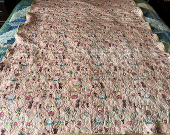 May include: A large, quilted blanket with a repeating pattern of brown bears and colorful flowers on a light pink background. The blanket has a scalloped edge and is lying on a bed.