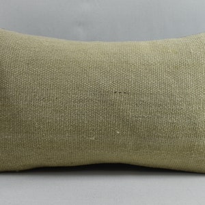 May include: A light beige rectangular cushion with a subtle woven texture. The cushion is made of a natural fabric and has a simple, understated design.