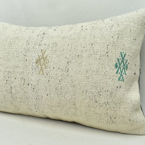 May include: White throw pillow with a geometric pattern in green and beige. The pillow is made of a soft, textured fabric.