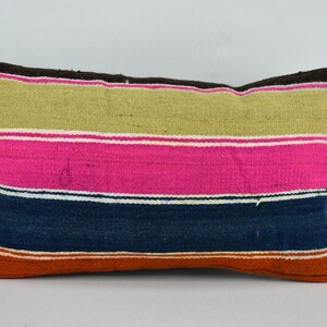 May include: A striped pillow cover with a brown, beige, pink, blue, and orange color scheme. The pillow cover is made of woven fabric and has a rectangular shape.