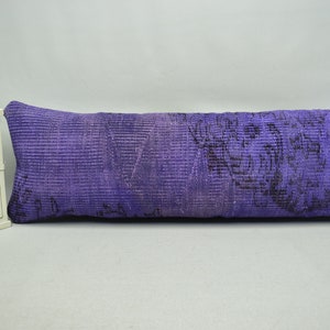 May include: A long, rectangular purple pillow with a floral pattern. The pillow is made of a soft, woven fabric and has a subtle sheen.