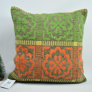 May include: A green, orange and yellow patterned cushion with a floral design. The cushion is made of a soft, textured fabric.