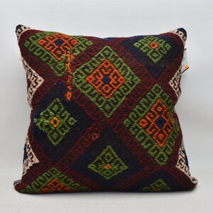 May include: Square cushion featuring a geometric diamond pattern in burgundy, navy, green, orange, and white. The cushion has a textured appearance, possibly woven or embroidered, and is suitable for home decor.