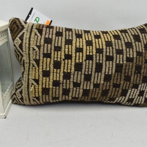 May include: A brown and beige patterned cushion with a geometric design. The cushion is made of woven fabric and has a rectangular shape.