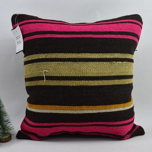May include: A brown and pink striped throw pillow with a woven texture. The pillow has a light brown, beige, and white stripe in the center.