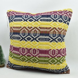 May include: A yellow, blue, green and red patterned throw pillow with a geometric design.