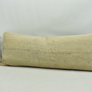 May include: A long, rectangular, off-white cushion with a woven texture. The cushion is made of a natural fibre and has a slightly rough surface.