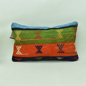 May include: A rectangular pillow with a colorful geometric pattern. The pillow has stripes of green, orange, blue, and black with a white and yellow geometric design.