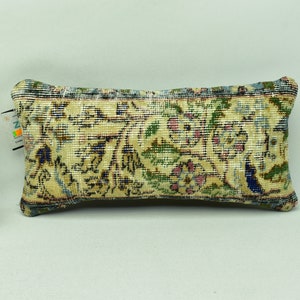 May include: A decorative cushion with a floral pattern in shades of beige, blue, green, and pink. The cushion is made from a woven fabric with a textured surface.