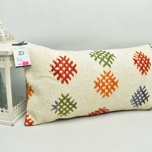 May include: A white rectangular cushion with a colourful geometric pattern. The pattern features red, orange, green and blue squares.