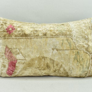 May include: A rectangular cushion with a beige background and a faded floral pattern in shades of pink, green, and white. The cushion is made of a soft, textured fabric.