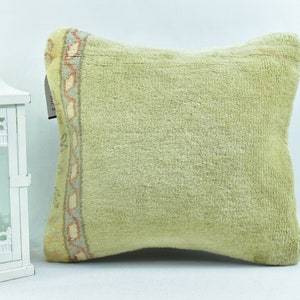 May include: A light green throw pillow with a decorative border featuring a geometric pattern in shades of peach, cream, and blue.