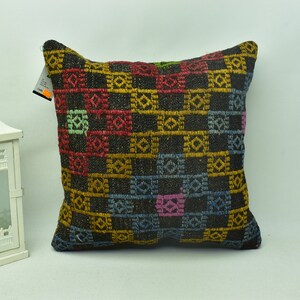 May include: A square cushion with a black background and a colourful geometric pattern. The pattern features squares of yellow, red, blue, green, and pink.