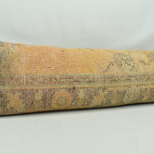 May include: A long, rectangular cushion with a woven fabric cover. The fabric is a mix of beige, brown, and blue, with a geometric pattern. The cushion is ideal for adding a touch of bohemian style to any room.