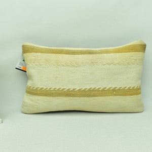 May include: A white and beige striped throw pillow with a woven texture. The pillow is rectangular and has a subtle sheen.