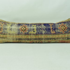 May include: A long, rectangular cushion with a colourful, patterned design. The cushion is made of a woven fabric with a blue, yellow, and red colour scheme. The pattern features geometric shapes and floral motifs.