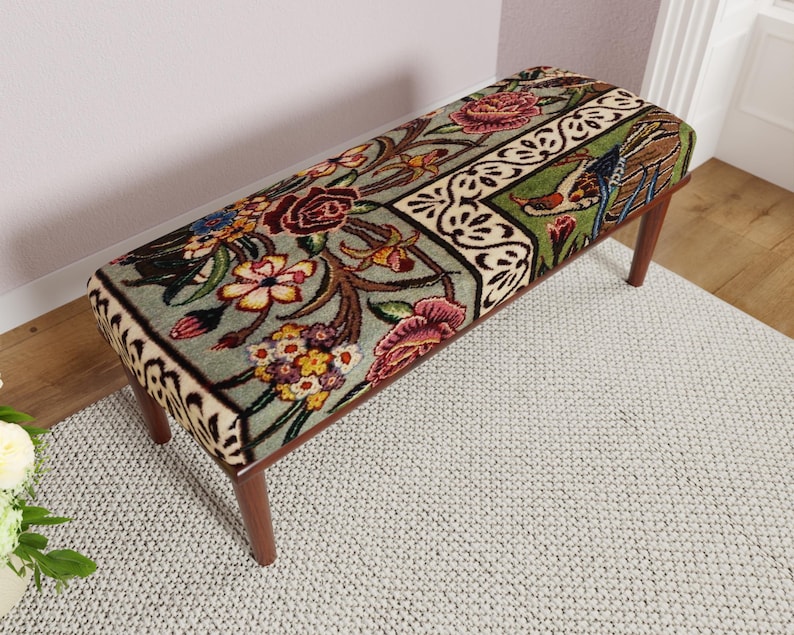 Puede incluir: Banco rectangular con un estampado floral en tonos rojos, amarillos y verdes. El banco tiene un fondo verde claro con un dise&ntilde;o floral detallado. Las patas son de madera oscura.