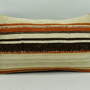 May include: A striped throw pillow with a beige background, brown and orange stripes. The pillow is made of woven fabric.