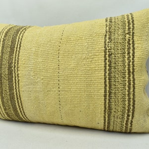 May include: A rectangular throw pillow with a woven design. The pillow is made of a light yellow fabric with brown stripes.