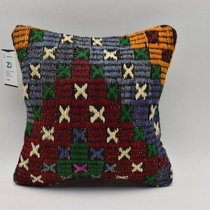 May include: A colourful patterned cushion with a geometric design in shades of red, blue, green, yellow, and white. The cushion is made of woven fabric and has a square shape.