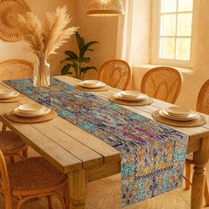 Può includere: Un lungo runner da tavolo fantasia nei toni del grigio, blu e arancione adorna un tavolo da pranzo in legno apparecchiato per un pasto. Sedie e sottopiatti in vimini completano l'apparecchiatura. Un vaso di fiori secchi e un lampadario completano l'arredamento della stanza.