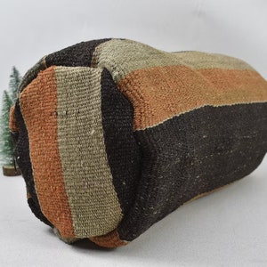 May include: A striped woven pillow with brown, beige, and orange stripes. The pillow is made of a soft, textured fabric.