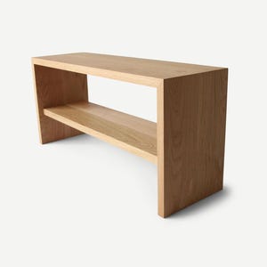 May include: A light wood bench with a shelf underneath. The bench is made of solid wood and has a simple, modern design.