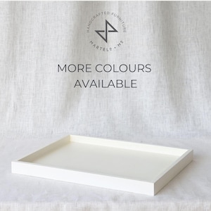 Könnte beinhalten: Weißes rechteckiges Serviertablett mit erhöhtem Rand. Das Tablett ist aus Holz und hat eine glatte Oberfläche. Der Text "MORE COLOURS AVAILABLE" ist in Schwarz auf weißem Hintergrund gedruckt.