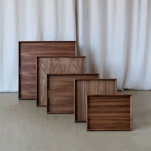 Puede incluir: Cinco bandejas de madera de diferentes tama&ntilde;os, todas hechas del mismo madera marr&oacute;n oscuro con un patr&oacute;n de veta de madera natural. Las bandejas est&aacute;n apiladas una encima de la otra, con la bandeja m&aacute;s grande en la parte inferior y la bandeja m&aacute;s peque&ntilde;a en la parte superior.