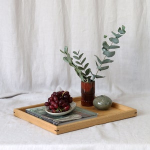 Oak ottoman tray styled  with plant, books and grapes.