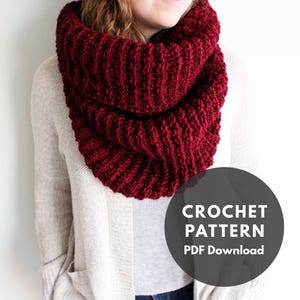 May include: A burgundy crochet infinity scarf. The scarf is thick and chunky, and it is worn by a person in the image. The image also includes text that says "CROCHET PATTERN PDF Download".