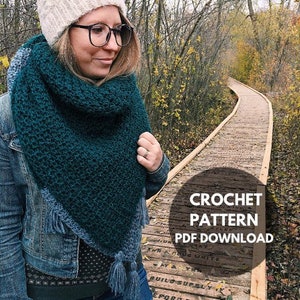 May include: A teal blue crochet scarf with a fringe border and tassels. The scarf is worn by a person standing on a wooden walkway. The text "CROCHET PATTERN PDF DOWNLOAD" is on a black circle.