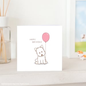 May include: A white card with a cartoon white dog holding a pink balloon. The card says "Happy Birthday!" in brown text.