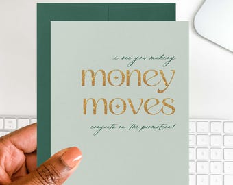 May include: A light green greeting card with the words "money moves" in gold glitter lettering. The card is held in a hand and has a dark green envelope behind it. The text "I see you making" and "congrats on the promotion!" are also on the card.