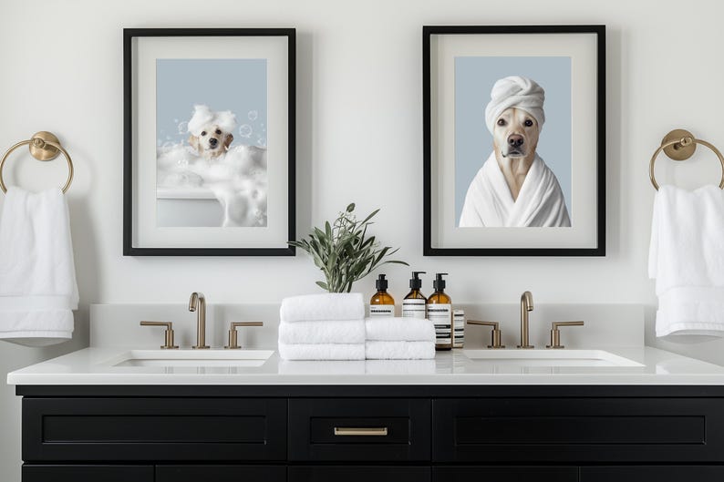 Pu&ograve; includere: Due stampe incorniciate di un cane in un bagno. Le stampe sono incorniciate di nero e mostrano un cane bianco in un bagno e un cane bianco che indossa un asciugamano bianco. Il bagno ha un doppio lavabo con due lavandini e rubinetti dorati. Ci sono asciugamani e bottiglie di sapone liquido sul bancone.