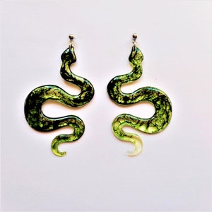 May include: A pair of green snake-shaped earrings with a silver hook. The earrings are made of resin and have a marbled effect.