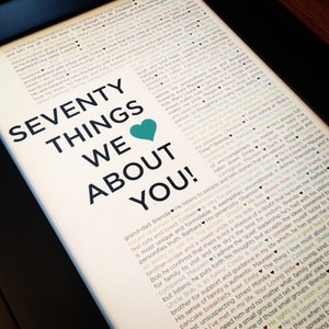 Könnte beinhalten: Ein gerahmter Druck mit dem Text "SEVENTY THINGS WE ABOUT YOU!" in großen Buchstaben, mit einem türkisfarbenen Herz. Der Hintergrund ist mit kleinerem Text gefüllt, wahrscheinlich eine Liste von Eigenschaften oder Erinnerungen.
