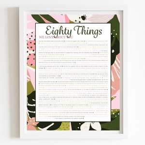 May include: A framed print with the text "Eighty Things We Love About You" in a decorative font. The print has a white border and a colorful floral design in pink, green, and white. The text is in black.