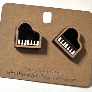 May include: A pair of wooden piano earrings. The earrings are shaped like a grand piano with black and white keys. The earrings are on a brown card with the text "handmade by RhythmicallyYours.etsy.com".