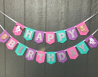 May include: A pink, purple, and teal banner with silver glitter letters that reads "Happy Birthday". The banner has small dog cutouts on each end.