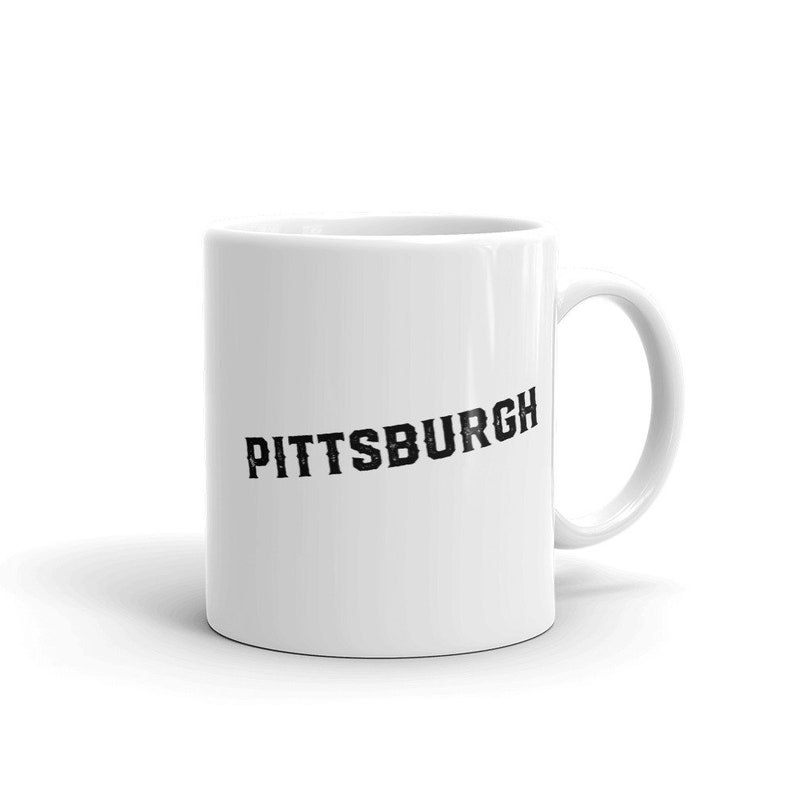 May include: White ceramic coffee mug with a black graphic that says "PITTSBURGH" in a distressed font.
