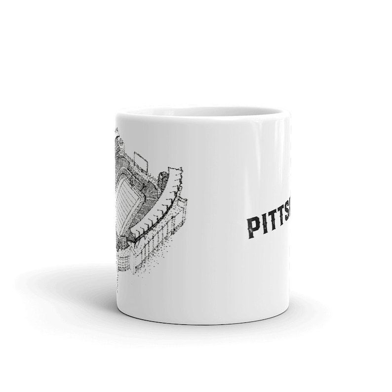 May include: White ceramic mug featuring a black and white illustration of a football stadium on one side and the word "PITTS" on the other.