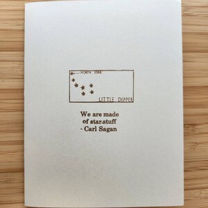 May include: A white card with a brown illustration of the Little Dipper constellation and the text "We are made of star-stuff - Carl Sagan".