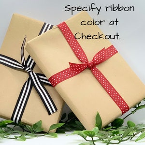 May include: Two brown gift boxes wrapped with ribbon. One box is tied with black and white striped ribbon, the other with red ribbon with white polka dots. The text "Specify ribbon color at Checkout." is written in black on a white background.