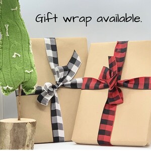 May include: Two gift boxes wrapped in brown paper with black and white checkered ribbon and red and black checkered ribbon. The text "Gift wrap available." is written above the boxes.