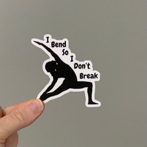 May include: Black and white sticker with a silhouette of a person in a yoga pose. The text "I Bend So I Don't Break" is written around the silhouette.