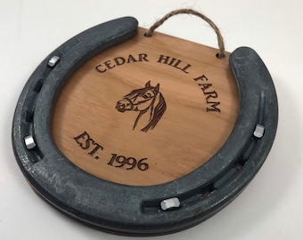 May include: A wooden sign with a horseshoe frame, engraved with the text "Cedar Hill Farm Est. 1996". A horse's head is also engraved on the sign.