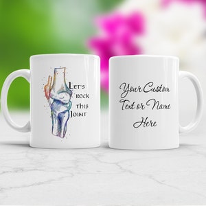 Puede incluir: Taza de café de cerámica blanca con una ilustración colorida de una articulación de la rodilla y el texto "Let's rock this joint". El otro lado de la taza tiene el texto "Your Custom Text or Name Here".